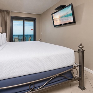 Spacious master suite featuring a plush king bed and a large window with views of the balcony and beyond