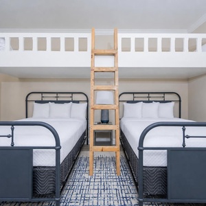 Charming bunk room with two twin beds lofted above two queens, and a warm atmosphere for a cheerful stay