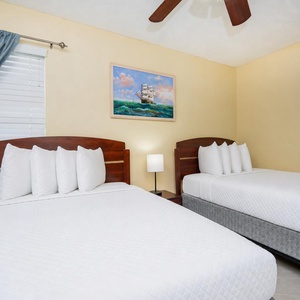 This guest bedroom features two comfortable beds, bright white linens, and cheerful nautical artwork for a relaxing stay
