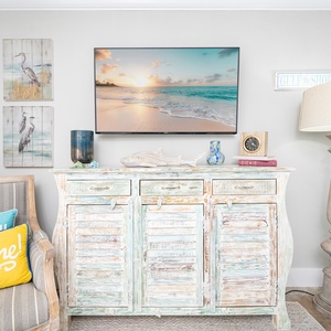 Living space features a vintage-style console, vibrant pillows, and a wall-mounted TV waiting for your vacation to begin