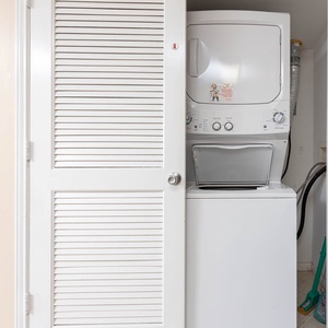 The laundry area features a stacked washer and dryer behind white louvered doors, providing convenience for guests