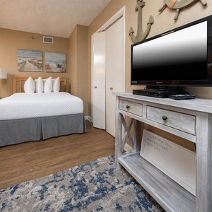 Cozy guest bedroom featuring a double bed, a twin over full bunk, a flat-screen TV, and charming coastal decor