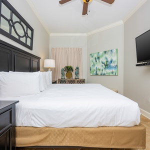 This cozy bedroom features a large king bed, a mounted TV, and decorative accents, creating a relaxing retreat