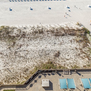 Relax on the balcony, enjoying the spacious pool area with lounge chairs and easy access to the beach just steps away