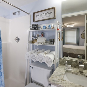 The guest bathroom features a stylish blue shower curtain, plush towels, and a sleek granite countertop for a refreshing experience
