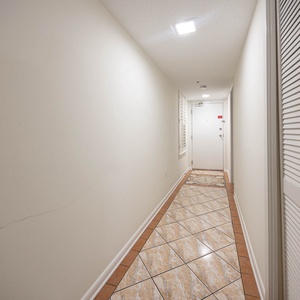 Welcoming hallway featuring elegant tile flooring, leading to the entrance door inviting guests into a relaxing retreat