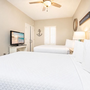 Relax in this cozy guest bedroom, where two queen beds invite you to unwind and catch up on your favorite shows