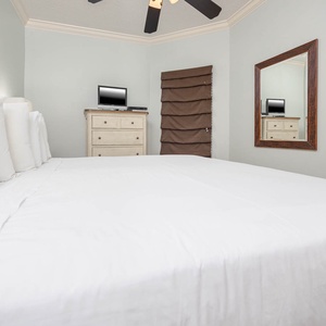 Serene guest bedroom featuring a queen bed, stylish decor, and a convenient TV for your entertainment