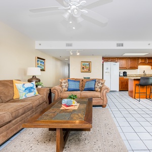 Living area featuring a cozy sofa, a wooden coffee table, and a view of the kitchen with wooden cabinetry