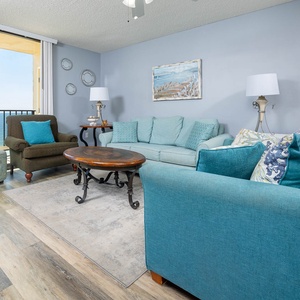 Bright living area featuring teal furnishings with queen sleeper and chair sleeper, stylish coffee table, and balcony access