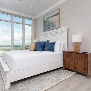 Wake to morning light and coastal views through tall windows while resting in this king guest suite