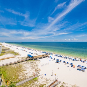 This balcony view showcases a stunning beachfront with vibrant blue umbrellas and soft white sand, perfect for relaxation
