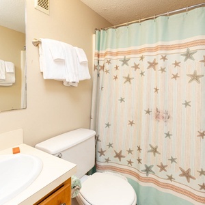 This bathroom features a clean design with a starfish-patterned shower curtain and fresh towels for a refreshing stay