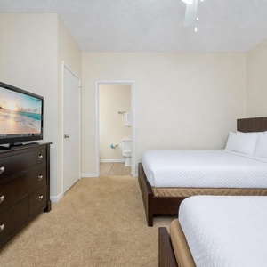 Cozy guest bedroom featuring a dresser, TV, and two queen beds