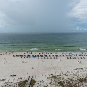 A serene beach view showcases vibrant blue umbrellas lining the shore, inviting guests to relax on the white sand