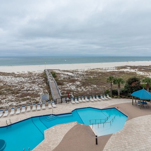 Relax by the inviting pool area, with lounge chairs and a view leading to the beach just steps away