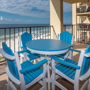 A vibrant blue table with matching chairs offers a perfect spot to enjoy the beach front view and gentle beach waves