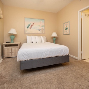 Serene guest bedroom featuring a queen bed, soft lighting, and beach decor for a restful stay