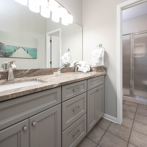 Master bathroom featuring a spacious vanity with a stone countertop, plush towels, and a walk-in shower behind a glass door