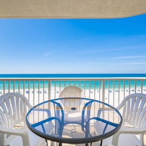 Enjoy a relaxing view from the balcony with a glass table and white chairs overlooking the beautiful beachfront