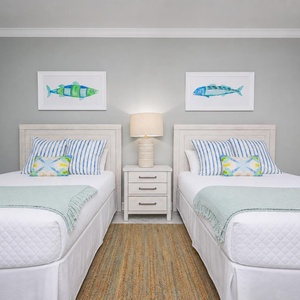Enjoy a bright guest bedroom with two queen beds, coastal decor, and cheerful artwork for a relaxing stay