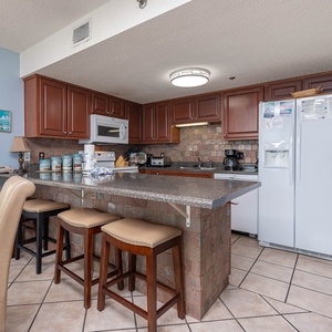 The fully-equipped kitchen features rich wood cabinetry, a breakfast bar with seating, and a stylish stone backsplash