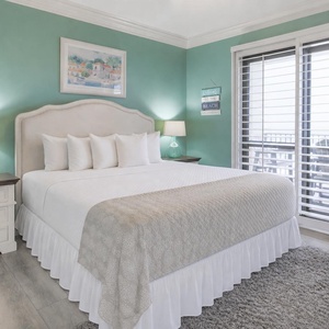 Serene master bedroom features a king bed with soft linens, a cozy rug, and access to a beachfront balcony
