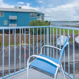 Enjoy a relaxing view of the lagoon from this balcony, featuring a blue chair perfect for unwinding