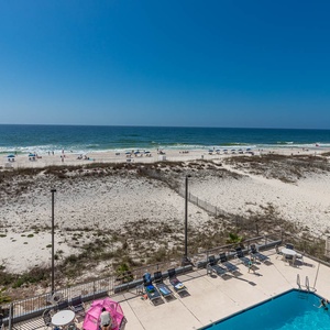 Enjoy a stunning beachfront view from the pool area, featuring lounge chairs and vibrant umbrellas for relaxation