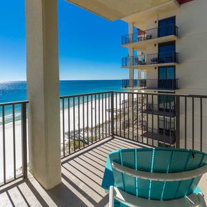Relax on the turquoise chair while enjoying the serene beachfront view from the private balcony