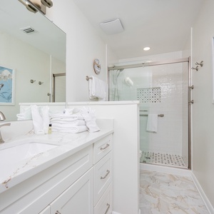 Master bathroom featuring a sleek vanity with a spacious sink, plush towels, and a walk-in shower with glass doors