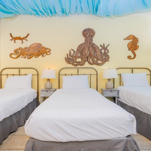 Colorful decor complements three twin beds with crisp white linens and stylish lamps in the cheerful indoor master patio