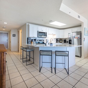 Gather around the large kitchen bar with seating, perfect for casual meals and conversation in a bright space