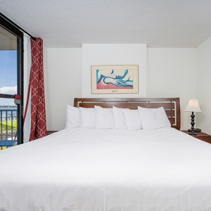 This bedroom features a plush white bed, vibrant artwork, and a lovely lagoon view from the large window