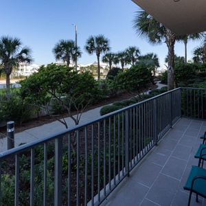 Guest balcony with comfortable seating, surrounded by lush greenery and views of palm trees swaying gently