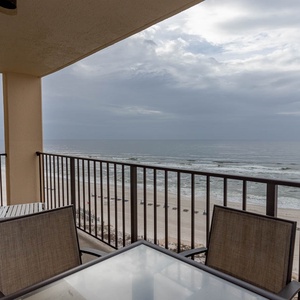 Relax on the balcony with comfortable seating, enjoying views of the serene beach and tranquil waves