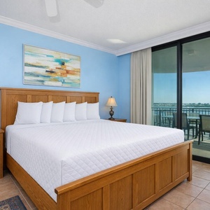 Master bedroom featuring a king bed, stunning bay view, and access to a private balcony with outdoor seating