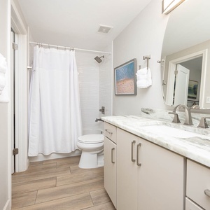 Experience this guest bathroom featuring a spacious vanity, modern fixtures, and a relaxing tub-shower with a textured wall
