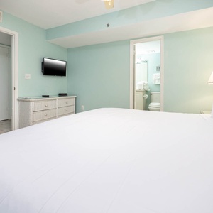 This bedroom features a serene color palette, a flat-screen TV, and an en-suite bathroom for added convenience