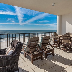 This spacious balcony features comfortable seating and a dining table, offering stunning beach views from the fourth floor