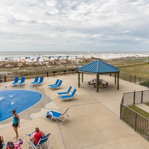 Pool area features a playful pirate ship splash park and loungers, with a view of the beach and colorful umbrellas