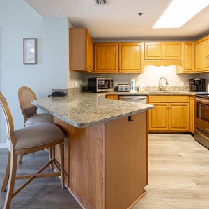 Warm wood cabinetry complements the granite countertops in this inviting kitchen area, featuring a breakfast bar with seating