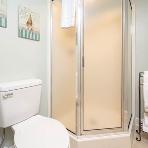 Brightly colored wall art complements the guest bath featuring a walk-in shower and neatly arranged white towels