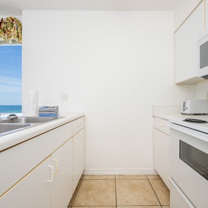 This kitchen features white cabinetry, essential appliances, and a convenient layout for preparing meals