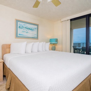 Spacious master bedroom featuring a king bed and large windows that provide beautiful views of the beach