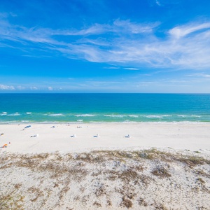 White sand stretches beneath a vast sky while gentle waves lap along the peaceful coast line