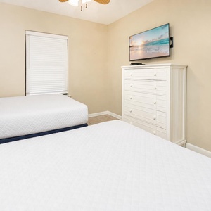 Enjoy restful nights in this guest bedroom featuring two twin beds, a TV, and cheerful decor for a relaxing stay