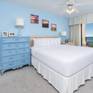 In the king master suite, you feel calm surrounded by gentle blue walls and a peaceful balcony view of the coast