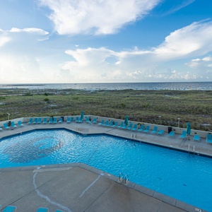 Inviting pool area with turquoise lounge chairs overlooks the beach, offering a serene spot to relax and enjoy the view