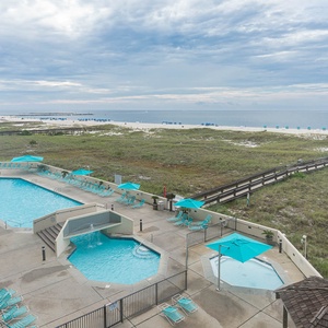 Pool area features inviting turquoise umbrellas and lounge chairs, leading to the beach with its serene white sand